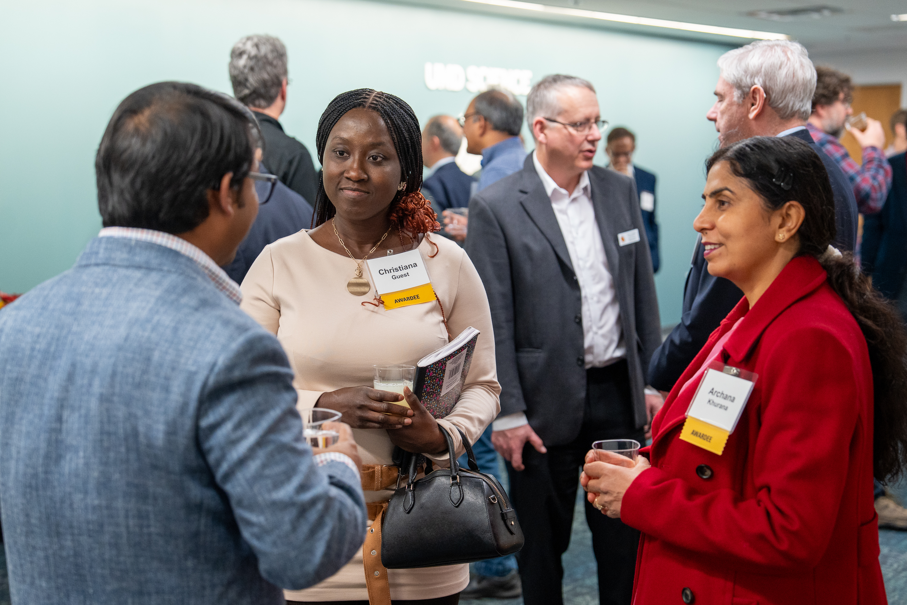 Three people talking at an event, and one person has their back to the camera