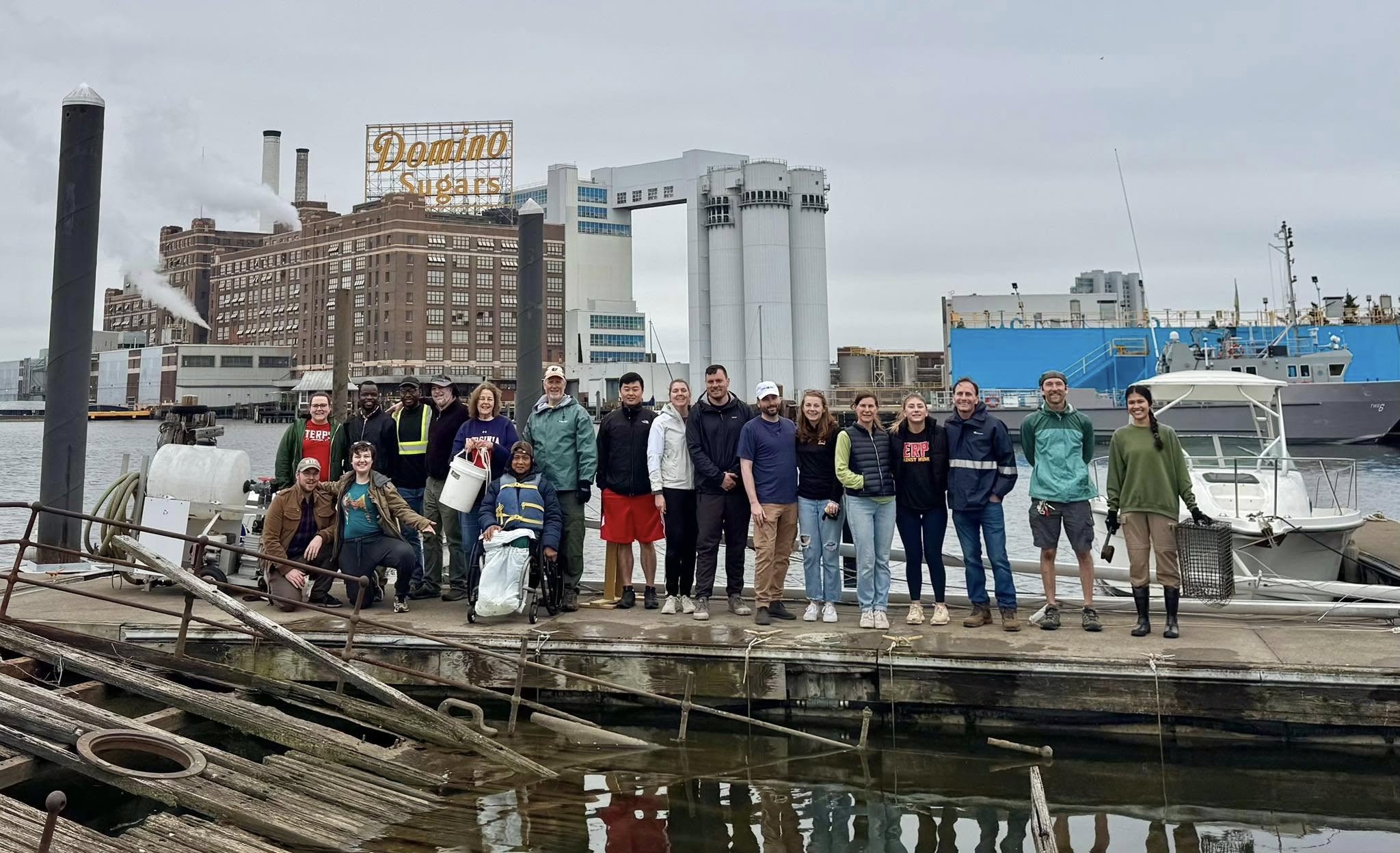 Group of people standing together at Baltimore's Inner Harbor with the Domino sugar sign in the backgroun