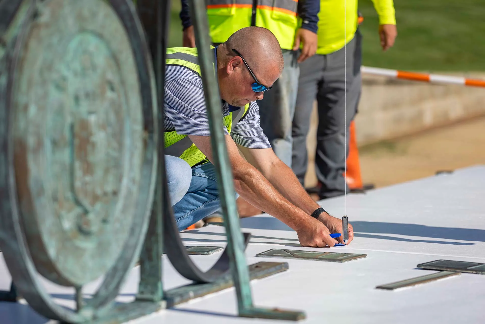 Professor Andrew Harris works with the facilities team to correct the placement of the month markers on the McKeldin Mall sundial on August 18, 2026.