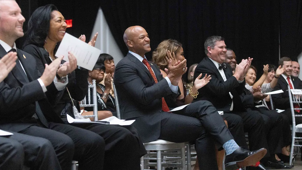 An audience of seated people claps.