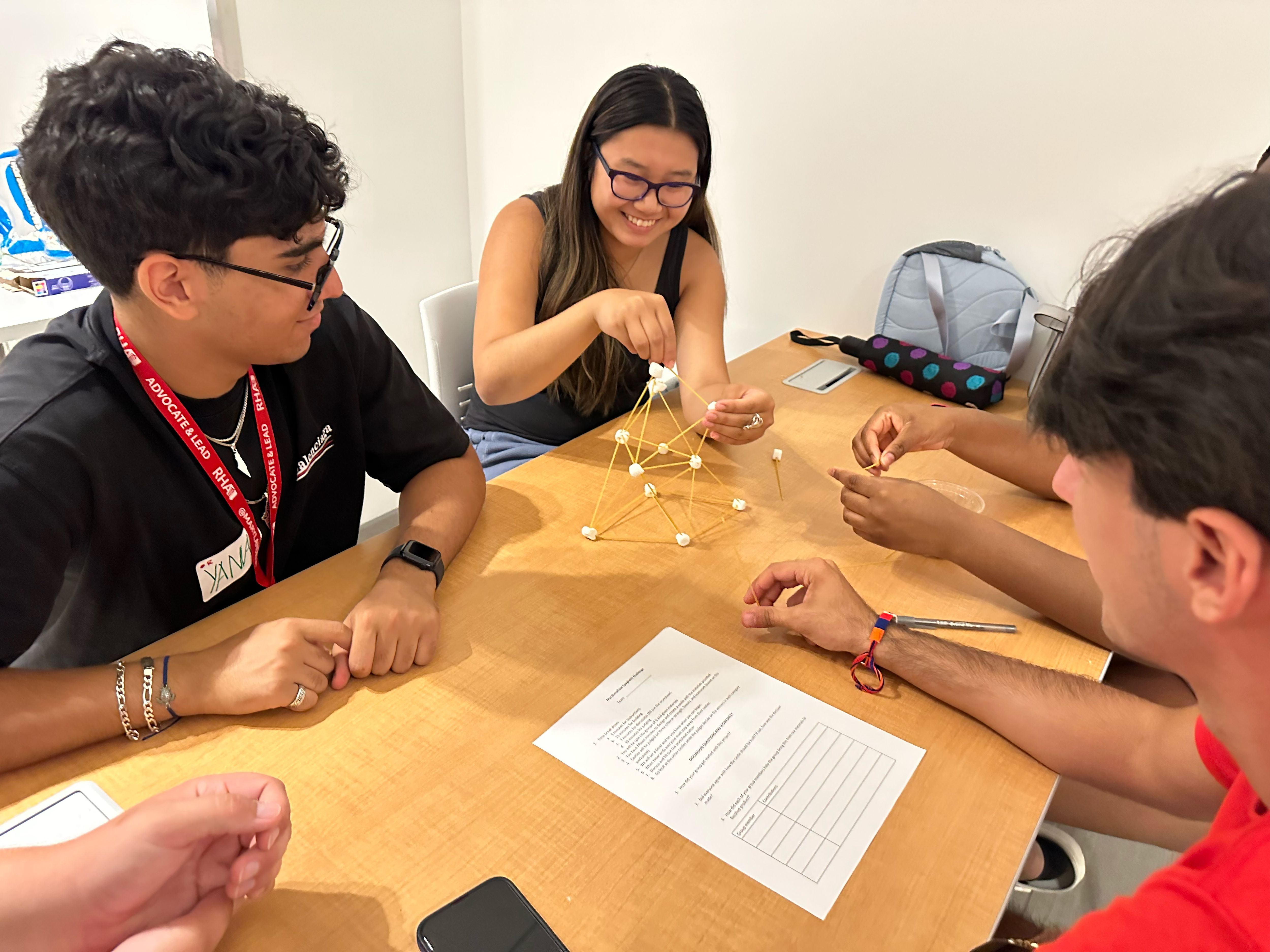 Students work together to build a castle out of spaghetti noodles and miniature marshmallows as part of a team-building competition.