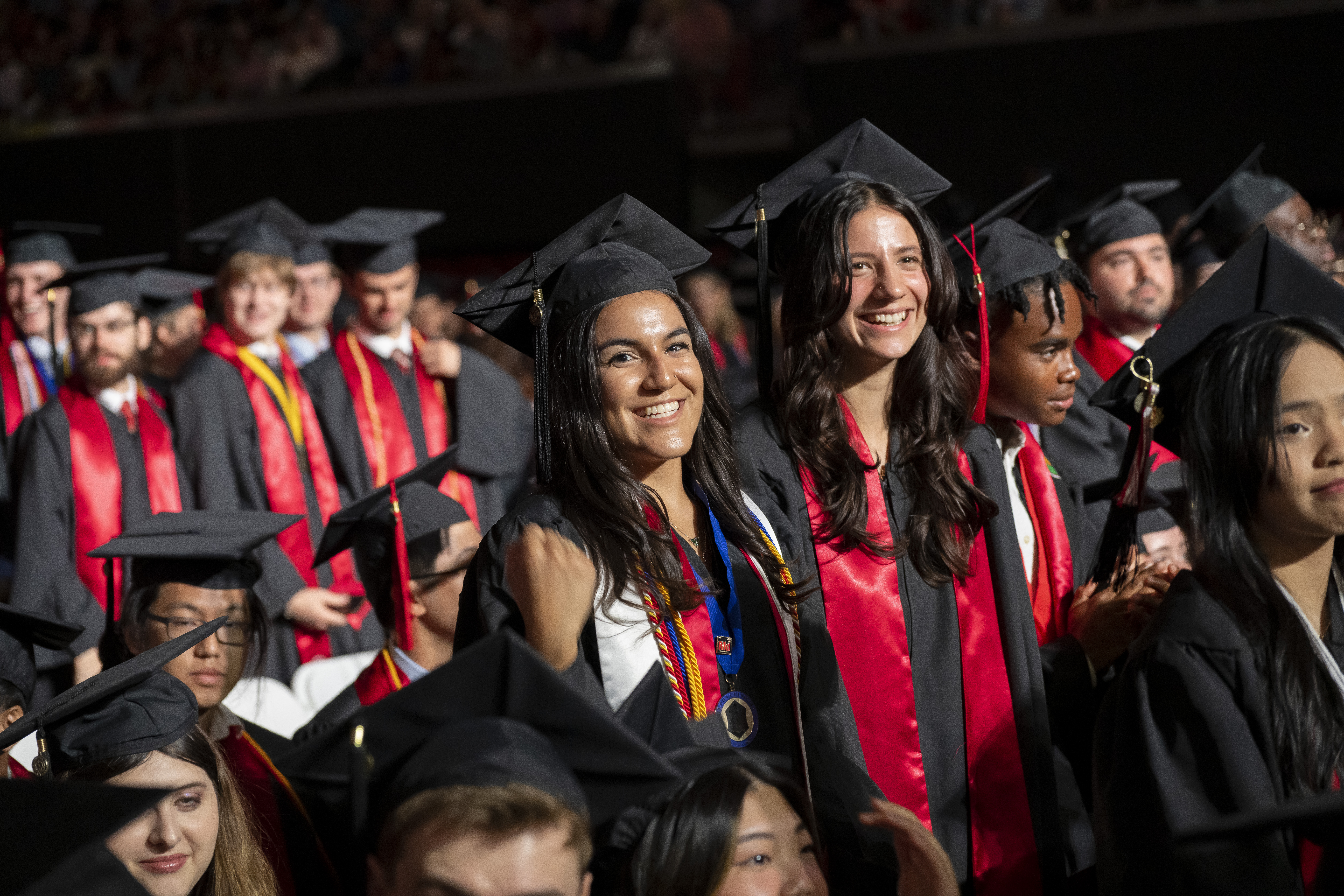 Graduates standing and smiling in full regalia
