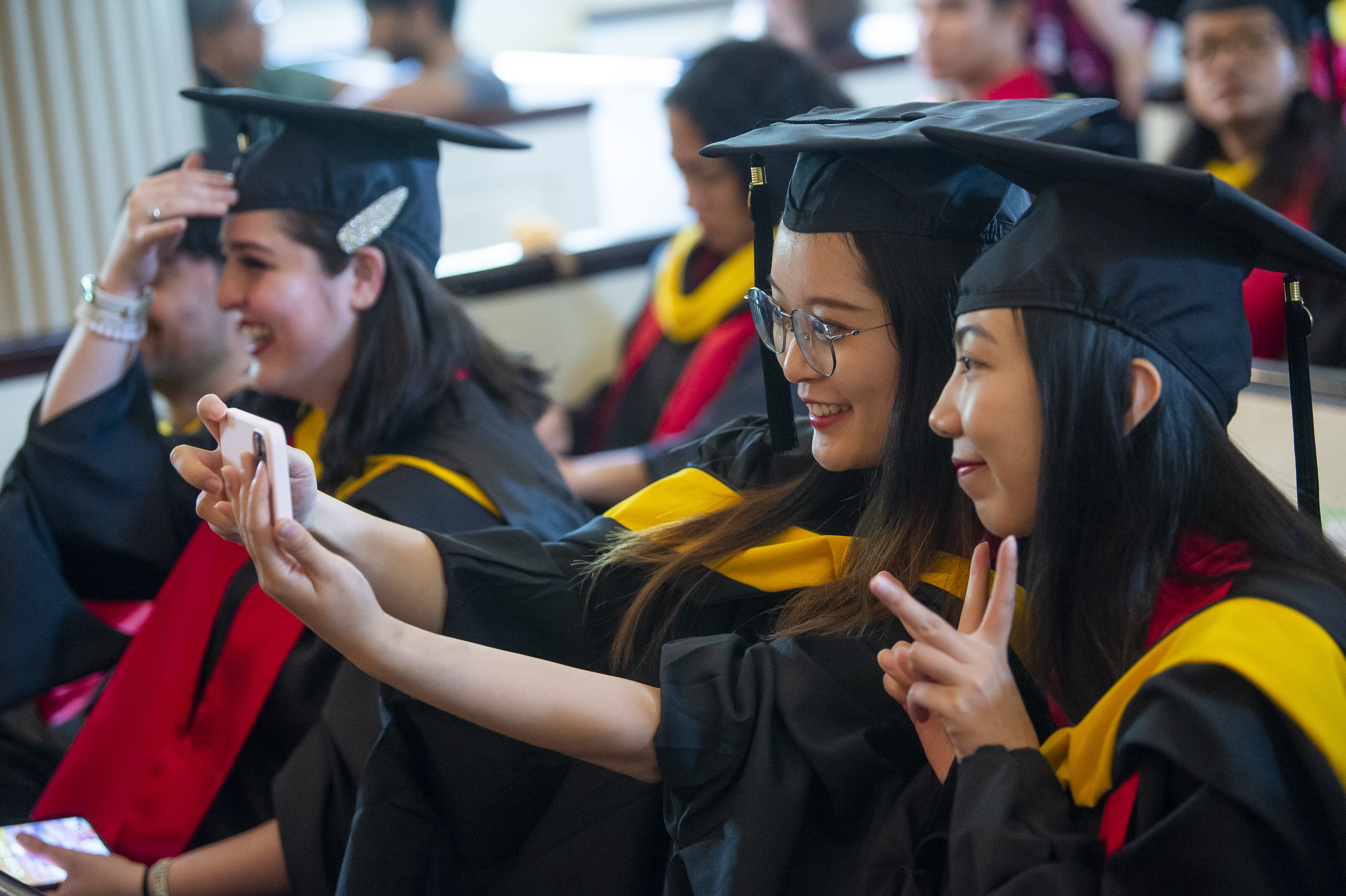 Graduate students taking selfies before the commencement ceremony