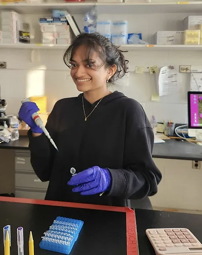 woman wearing gloves and pipetting in a biology lab