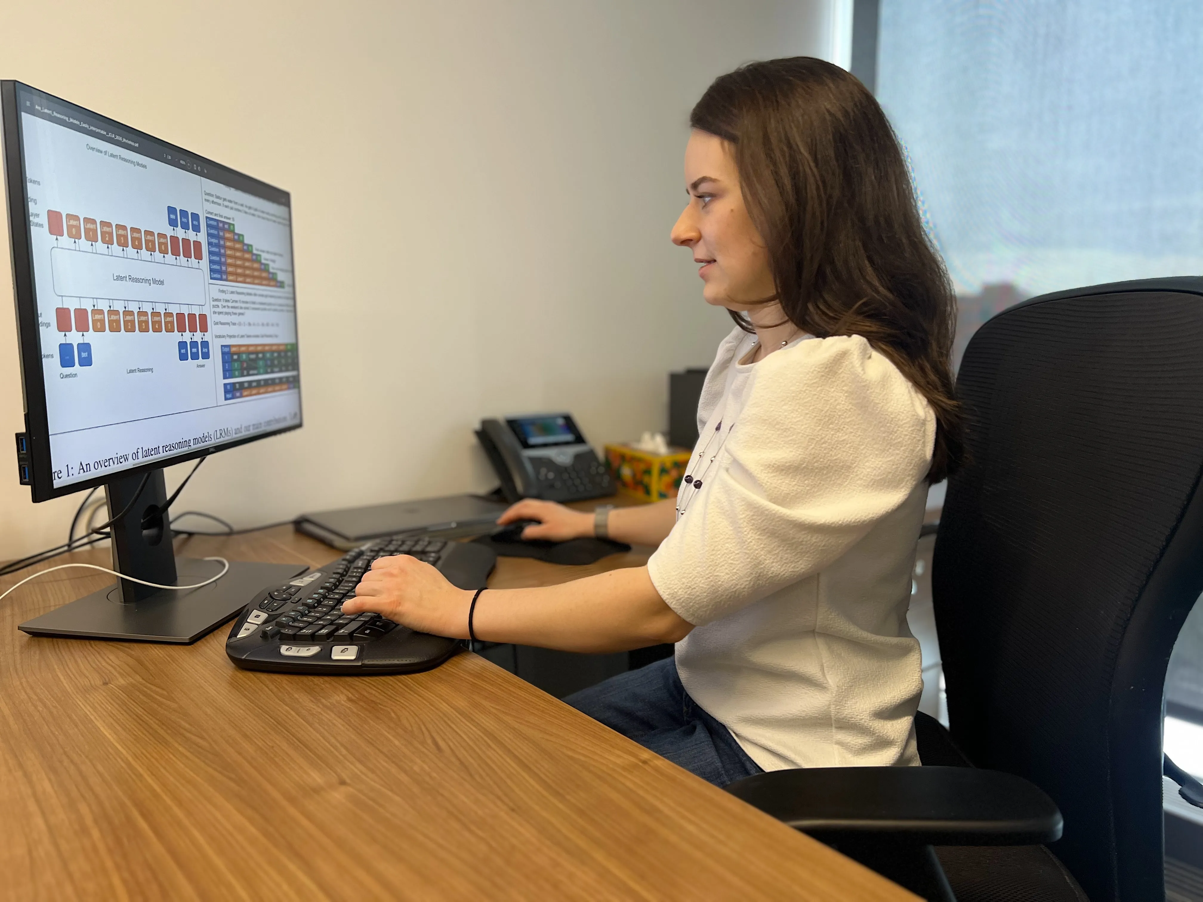 Sarah Wiegreffe sits at a computer, examining whether the reasoning processes used by advanced AI systems will remain transparent 