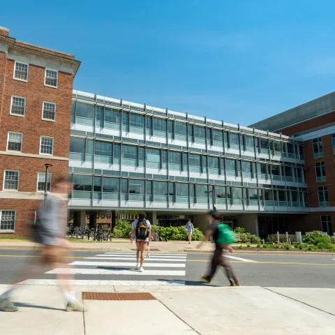 Blurred people walking in front of a red brick and glass building