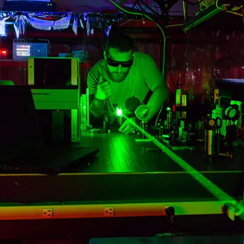 Person working in a dark room with a green laser