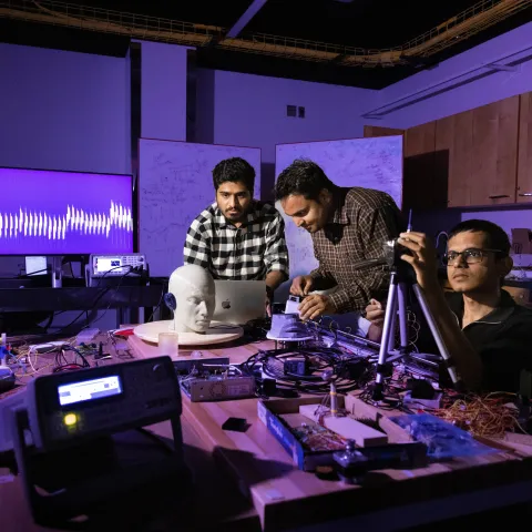 Three people working in a dark lab