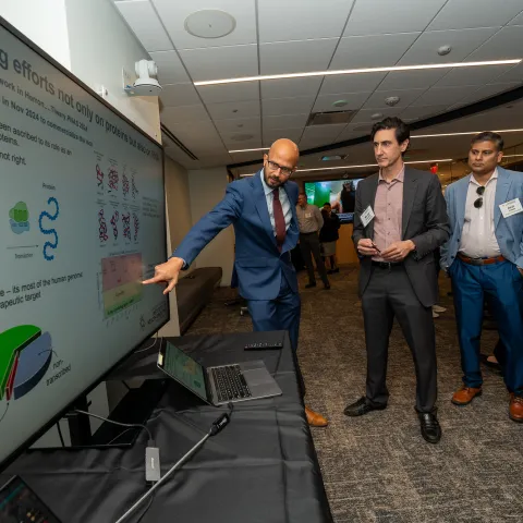 Man pointing at screen to explain research to a group of people