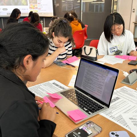 Three people working on resumes at a circular table