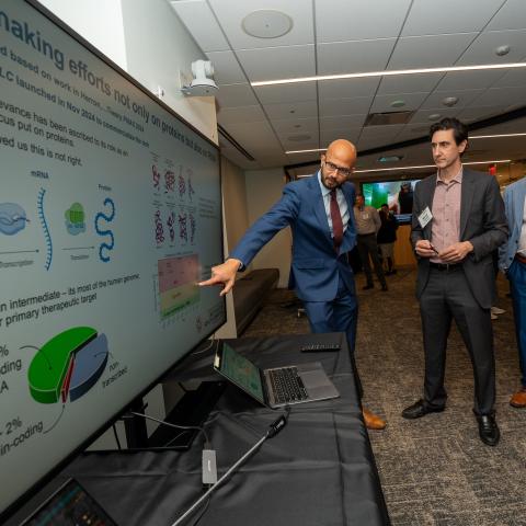 Man pointing at a screen to explain research slides