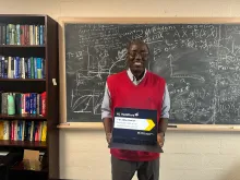 Mathematics Professor Abba Gumel standing in front of a chalkboard holding a laptop