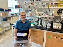 Carlos Machado holding a laptop in his lab