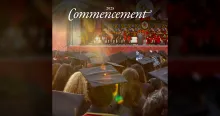 Photo of a large crowd of people at commencement. We see the students from the back, and ahead, a platform party facing the audience.