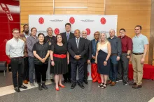 Group of employee awardees standing and smiling in front of a CMNS branded backdrop