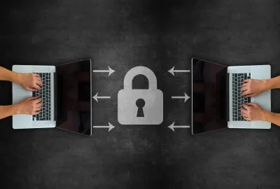Two sets of hands typing on laptops. In between then, there is a chalk graphic of a lock.