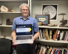 Thomas Holtz holding a laptop promoting his Reddit AMA