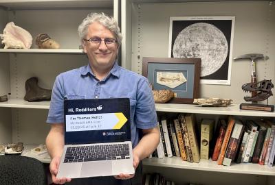 Thomas Holtz holding a laptop promoting his Reddit AMA