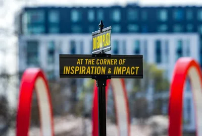 Road signs that read "Do Good Plaza" and "At the Corner of Inspiration & Impact"