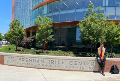 Fenil Gholani sitting in front of the Iribe Center in his graduation regalia