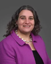 A portriat of Elana Fertig, director of the Institue for Genome Sciences, smiling in a purple jacket.
