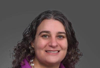 A portriat of Elana Fertig, director of the Institue for Genome Sciences, smiling in a purple jacket.