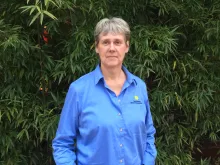 Sara Gallager in a blue Smithsonian shirt poses in front of bamboo.