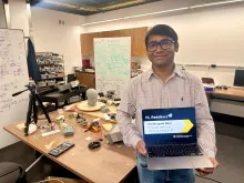Nirupam Roy holding a laptop promoting his Reddit AMA in his lab