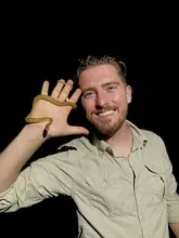 Jory van Thiel with a small non-venomous snake wrapped around his hand.