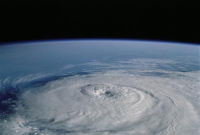 Aerial image of a hurricane from space, with white swirling clouds over a blue ocean.