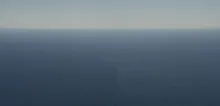 Aerial view of open ocean with a faint vertical streak marking a surface front amid calm blue water.