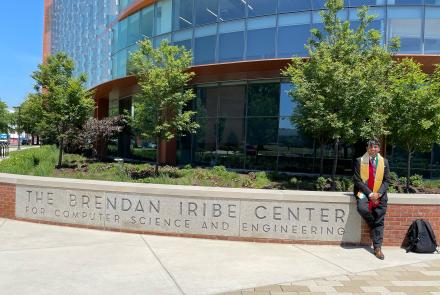 Fenil Gholani sitting in front of the Iribe Center in his graduation regalia