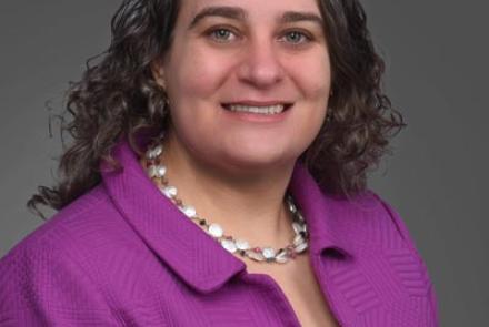 A portriat of Elana Fertig, director of the Institue for Genome Sciences, smiling in a purple jacket.