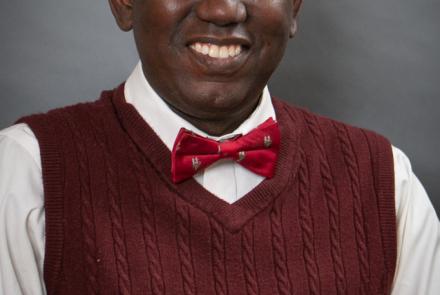 Abba Gumel smiling in a red sweater vest and red bow tie.
