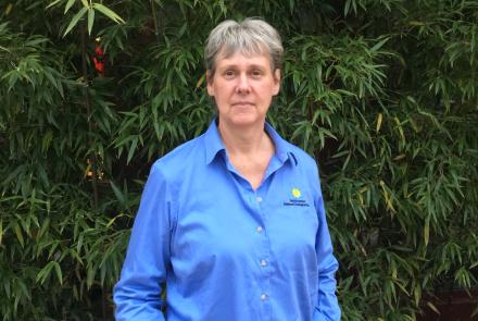 Sara Gallager in a blue Smithsonian shirt poses in front of bamboo.