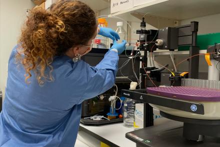  A woman in blue works at the bench in a lab.