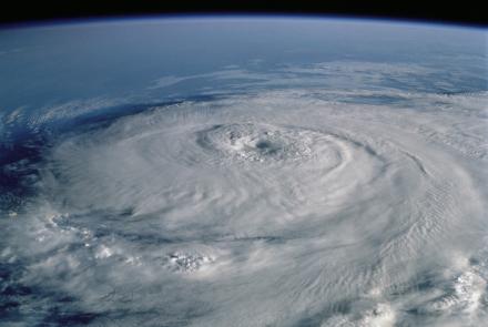Aerial image of a hurricane from space, with white swirling clouds over a blue ocean.