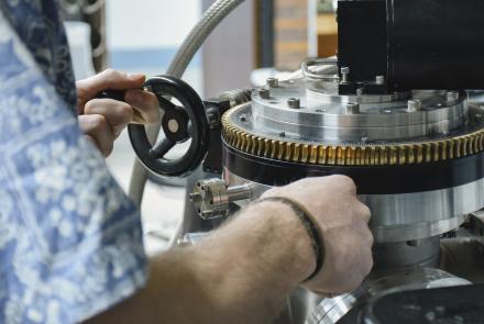 Two hands operating a silver piece of scientific equipment. 