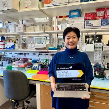 Kan Cao in her lab holding a laptop promoting her Reddit AMA