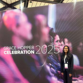 Nithika Ramanathan standing in front of the Grace Hopper Celebration 2025 banner