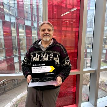 Alberto Bolatto holding a laptop in front of a window