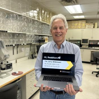 Jerry Wilkinson in his lab holding a laptop promoting his Reddit AMA
