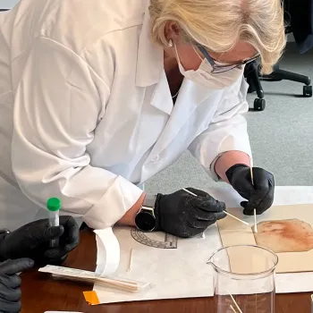 researcher in mask swabs back of "Holy Child"