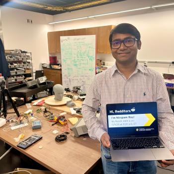 Nirupam Roy holding a laptop promoting his Reddit AMA in his lab