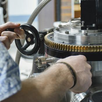 Two hands operating a silver piece of scientific equipment. 