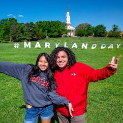 Two students with Maryland Day sign on Chapel Field