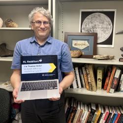 Thomas Holtz holding a laptop promoting his Reddit AMA