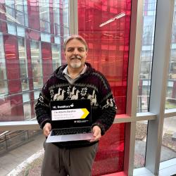Alberto Bolatto holding a laptop in front of a window