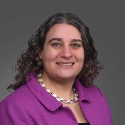 A portriat of Elana Fertig, director of the Institue for Genome Sciences, smiling in a purple jacket.