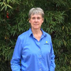 Sara Gallager in a blue Smithsonian shirt poses in front of bamboo.